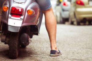 uomo con scooter che fa manovra in strada